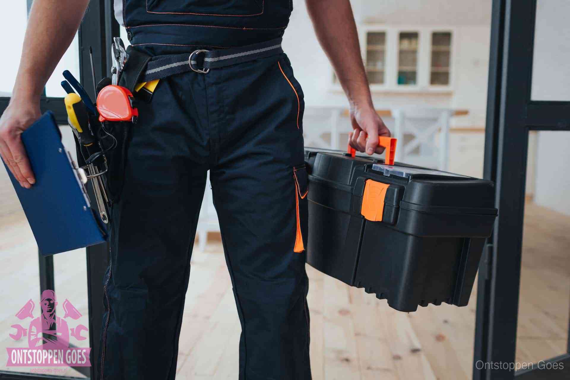Een monteur met gereedschapsriem en klembord in een keuken, klaar om een transparante prijs voor het gootsteen ontstoppen in Goes te geven