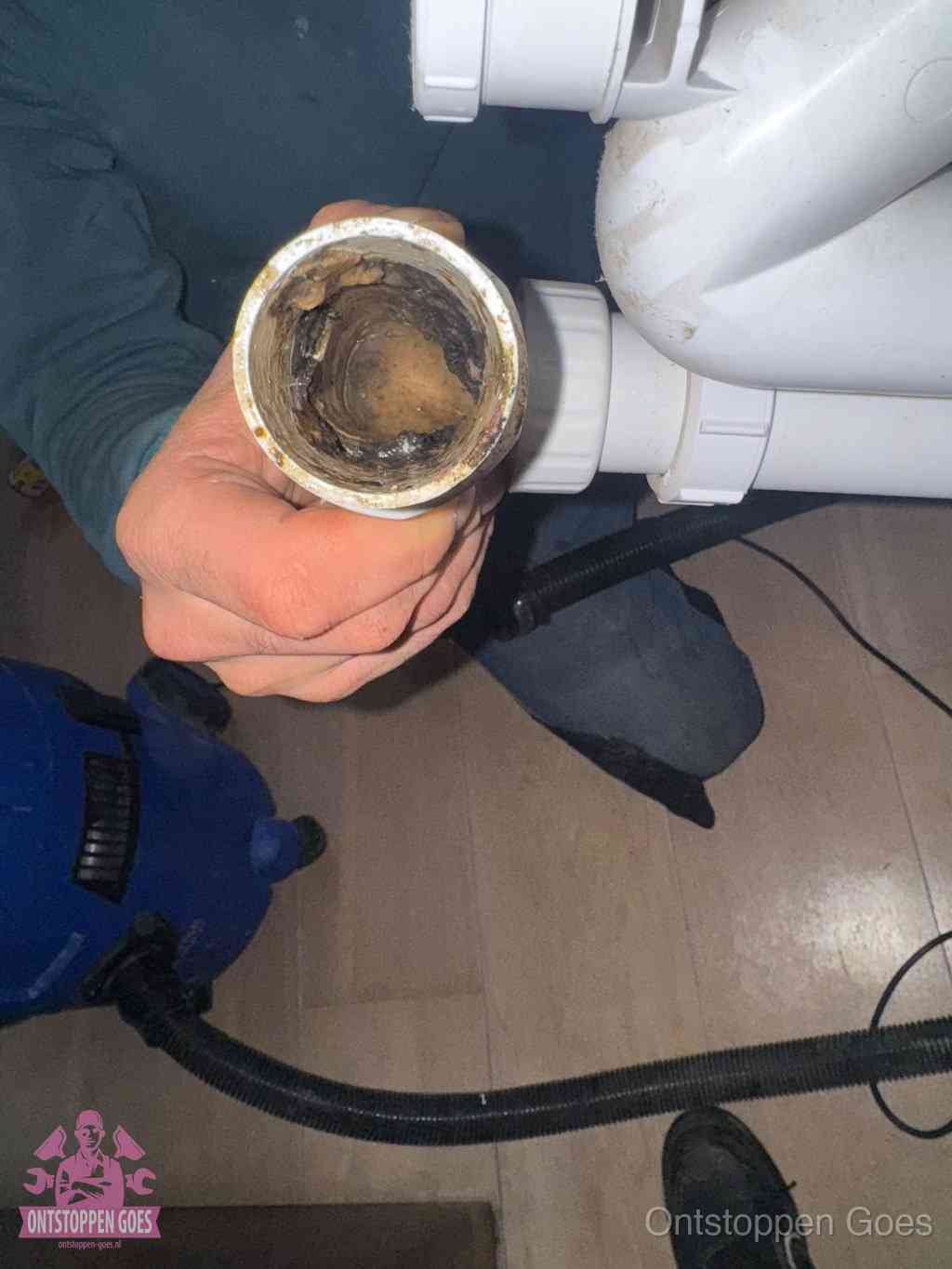 Een losgekoppelde afvoerbuis die van binnen volledig is dichtgeslibd met vet en aanslag, de meest voorkomende oorzaak van een verstopte gootsteen in Goes
