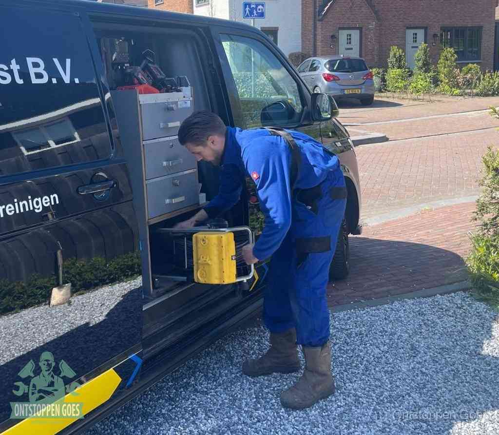 Een monteur pakt buiten op de oprit gereedschap uit de bedrijfsbus, het moment om een professional in te schakelen voor een verstopte afvoer in Goes