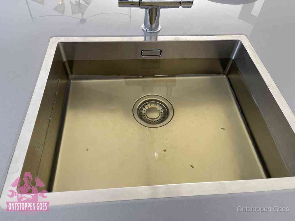 Stilstaand water in een rvs spoelbak dat niet wegloopt, een duidelijk signaal van een gootsteenverstopping in Goes