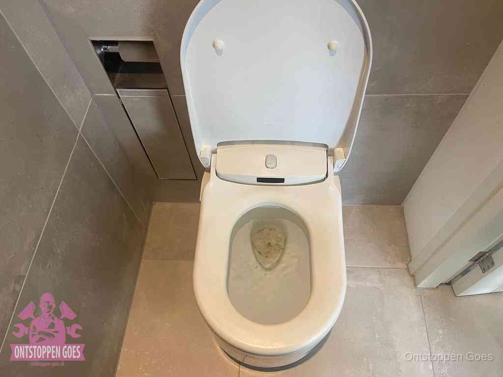 Een wit hangtoilet waarin een prop wc-papier op het water blijft drijven, een duidelijk signaal van een verstopte wc in Goes