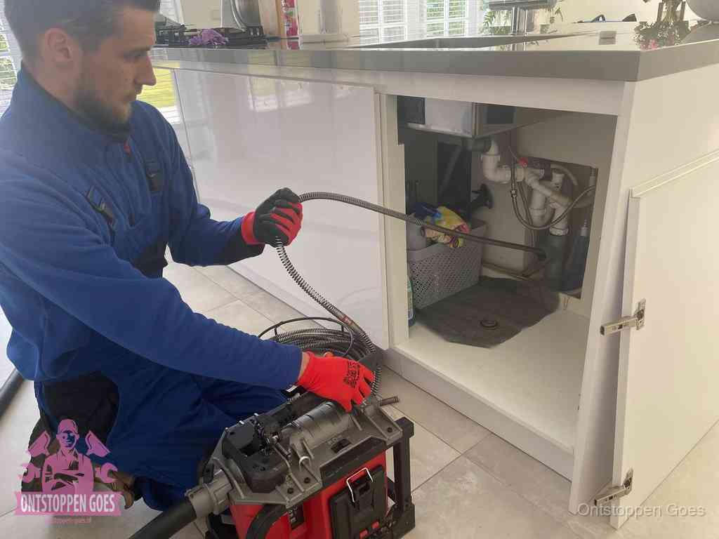 Een monteur reinigt de keukenafvoer grondig met een veermachine om terugkerende gootsteenverstoppingen te voorkomen in Goes