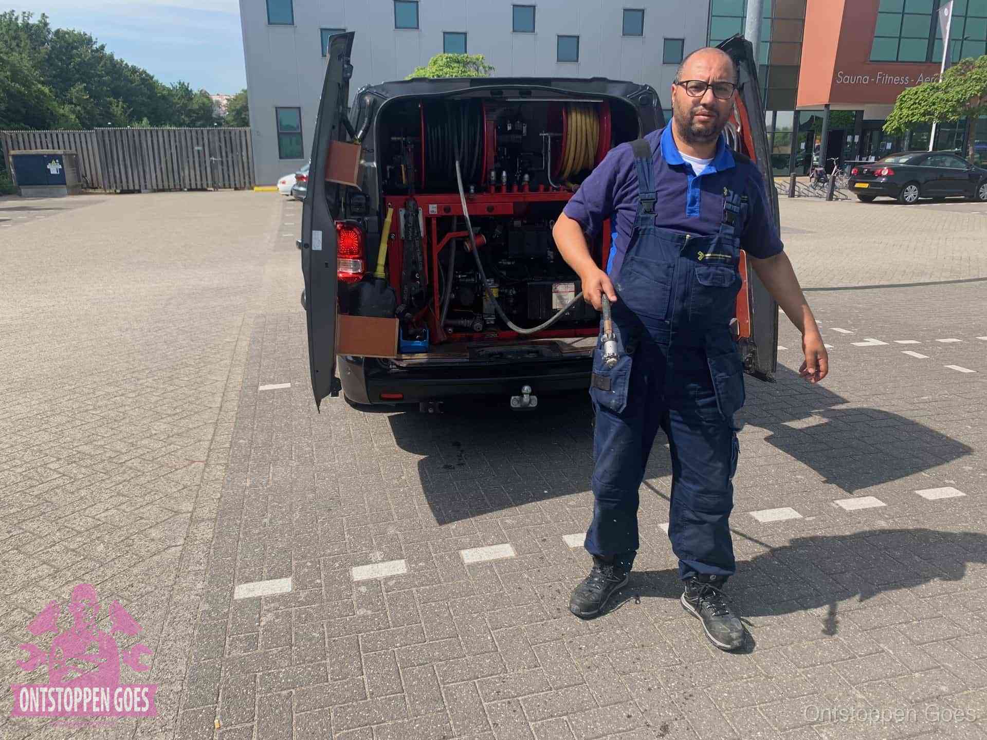 Een monteur bij zijn bestelbus met een hogedruk- en rioolreinigingsunit, klaar om de oorzaak van terugkerende wc-verstoppingen aan te pakken in Goes