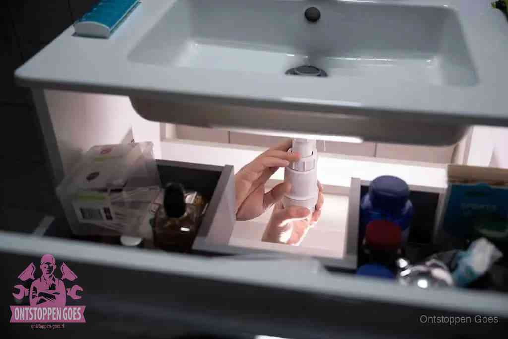 Een pompfles met zeep boven een wastafel in de toiletruimte, de warm water en afwasmiddel-methode om de wc te ontstoppen in Goes