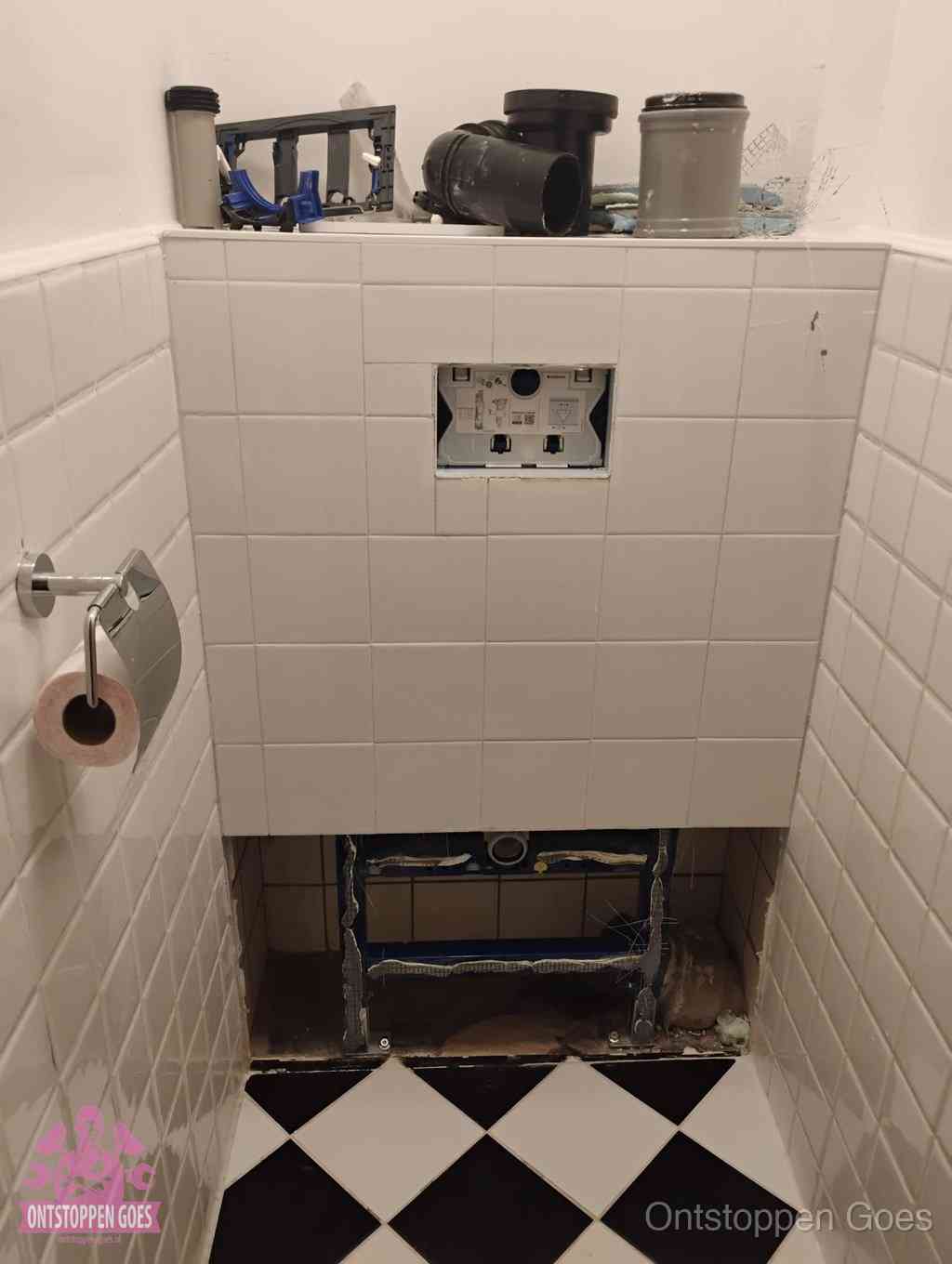 Een toiletruimte waar het hangtoilet en de inbouwreservoir-onderdelen zijn vrijgelegd voor onderhoud, periodiek nazicht voorkomt een wc-verstopping in Goes