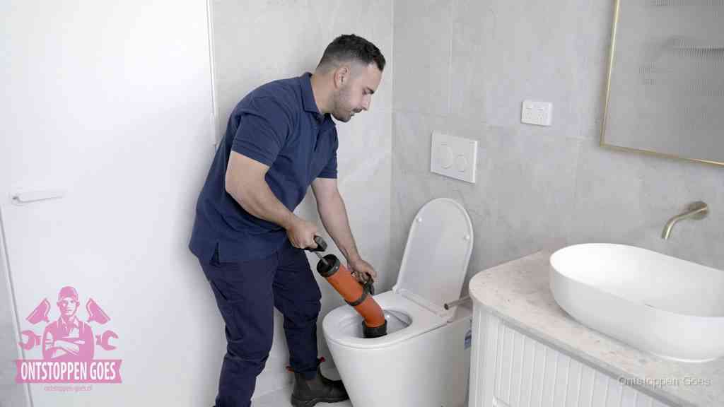 Een monteur gebruikt een handmatige perspomp (toiletontstopper) op een wandcloset tijdens het professioneel wc ontstoppen in Goes